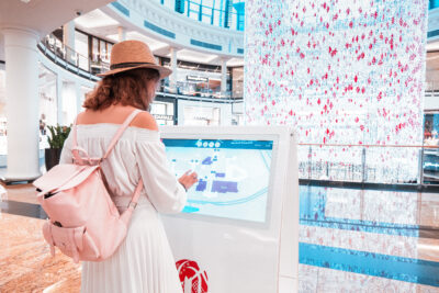 Femme utilisant une borne tactile installée dans un centre commercial